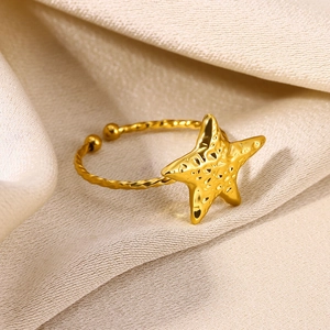 Close-up of golden starfish open ring with twisted rope band on beige silk