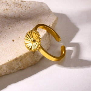 Close-up of golden daisy flower open ring with polished finish on a textured stone surface