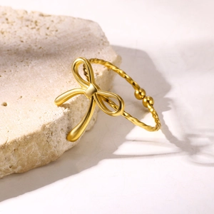 Macro shot of gold twisted bow bangle with elegant matte finish and smooth metal beads