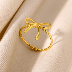 Polished gold bow ring with twisted rope band and adjustable open design on silk