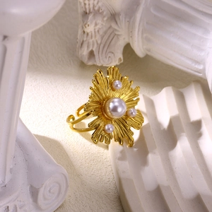 Detailed view of wide gold ring featuring multi-layer texture and large white center pearl