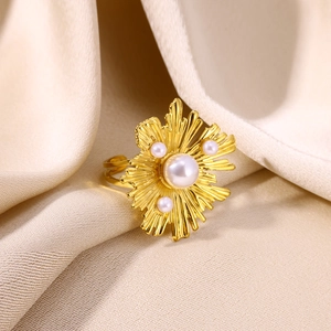 Detail of gold-plated sunburst ring with central pearl and adjustable double-row band