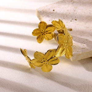 Golden flower petal cuff bracelet in stainless steel on marble base with shadows