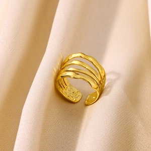 Macro detail of gold plated geometric multi-layer hollow ring on silk fabric