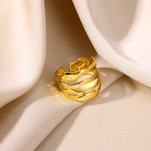 Detail of gold-plated geometric layered ring with hammered texture on silk fabric