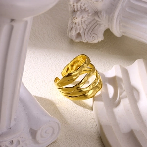 Detailed view of wide gold-plated layered wave ring on white architectural pillars