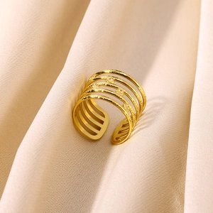 Detail of 18K gold-plated open ring with multi-layer hollow design on champagne silk