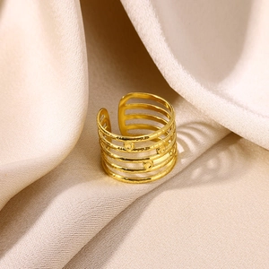 Detailed view of wide gold plated multi-layer ring with embossed dots on silk background