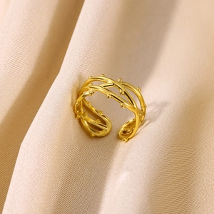 Macro shot of gold-plated multi-layer intertwined ring with bead texture on satin