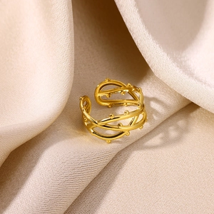 Detailed view of gold plated multi-layer branch ring with beads on beige silk fabric
