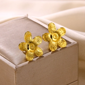 Nahaufnahme von 18K vergoldeten Blumenohrringen mit feinen Texturen auf einer Schmuckschatulle