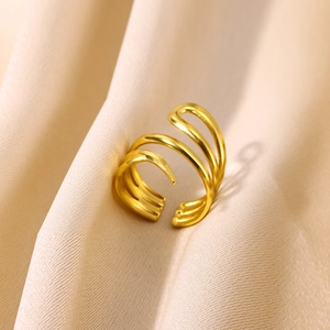 Macro detail of gold plated multi-layer spiral ring on elegant beige silk background