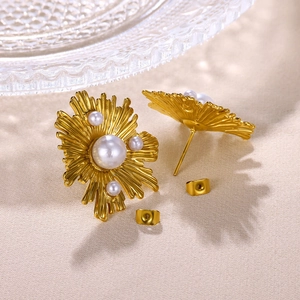 Detail von 18K goldene Edelstahl-Perlenohrringe mit Blumenstruktur auf beigem Stoff