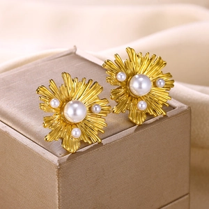 Nahaufnahme goldener Blumenohrringe mit Perle auf edlem Seidenhintergrund