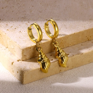 Detailed close-up of golden hoop earrings featuring elegant conch shell charms on stone