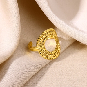 Macro shot of gold-plated hollow geometric ring with textured layers on satin fabric