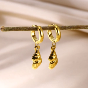 Macro detail of golden seashell hoop earrings hanging on a natural wood branch