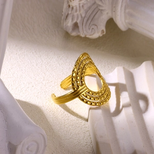 Macro view of gold plated layered geometric ring with hollow textured carved details