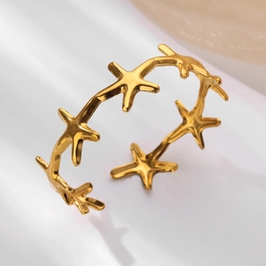 Detailed close-up of a gold starfish open bangle featuring textured metal sea motifs