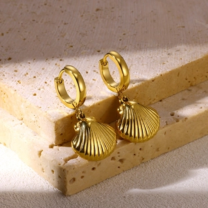 Macro shot of gold shell drop earrings featuring textured stripes on porous stone