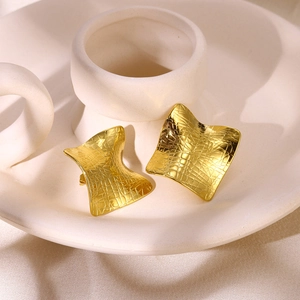 Detail of gold geometric earrings featuring embossed grid texture and wavy square design