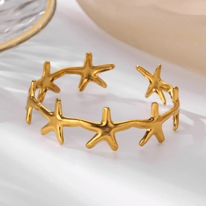 Detailed close-up of golden starfish open bracelet with a polished metallic finish