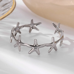 Close-up of a silver stainless steel open bangle featuring continuous starfish elements