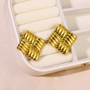 Close-up of gold-plated square earrings with unique woven texture on a white jewelry pad