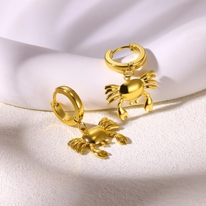 Macro shot of gold-plated crab pendant earrings with polished metallic finish