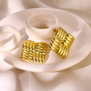 Macro detail of square gold earrings with geometric woven texture on 18K stainless steel