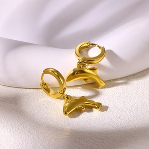 Detailed view of polished golden dolphin drop earrings on a minimalist white background