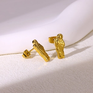Macro shot of gold-plated stainless steel religious portrait earrings with embossed texture