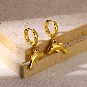 Detailed close-up of golden dolphin charms on polished hoops against a stone backdrop