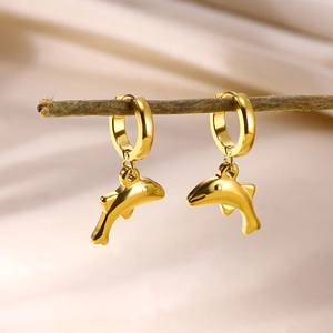 Golden dolphin hoop earrings with metallic finish hanging on a natural wooden branch
