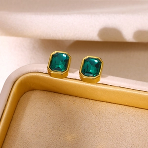 Close-up of vintage emerald cut green stone earrings in polished gold metal frames