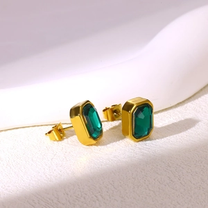 Close-up of gold-plated rectangular earrings with emerald green stones and butterfly backs