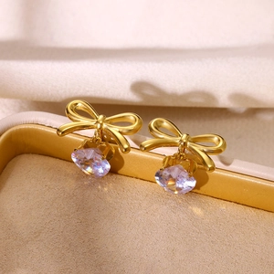Detailed macro view of gold-plated bow earrings featuring sparkling clear heart-cut zircons