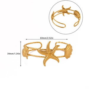 Detailed view of starfish and seashell motifs on gold stainless steel cuff bracelet