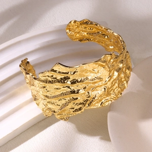 Detailed view of wide gold cuff bracelet featuring unique hammered lava texture on its surface