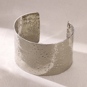Close-up of silver wide open bangle with hammered water ripple texture in stainless steel
