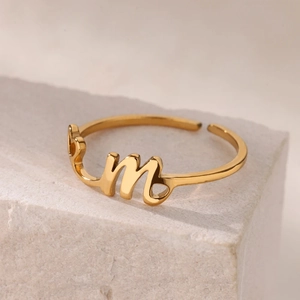 Anillo abierto de acero inoxidable bañado en oro con letra M y detalles de corazón