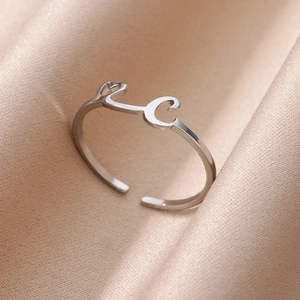 Vista detallada del anillo ajustable con letra L corazón C sobre tela de seda