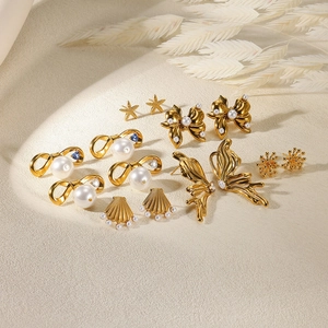 Coffret de boucles d'oreilles dorées avec perles et papillons sur un support texturé élégant
