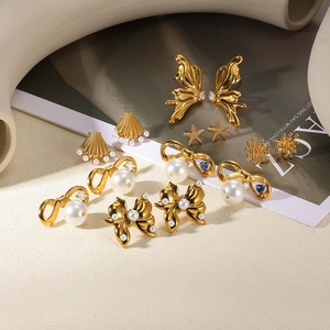 Détail de boucles d'oreilles papillon et perle dorées sur un fond texturé élégant