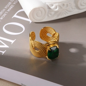 Detail of vintage gold-plated ring with emerald gemstone and woven texture on a pedestal