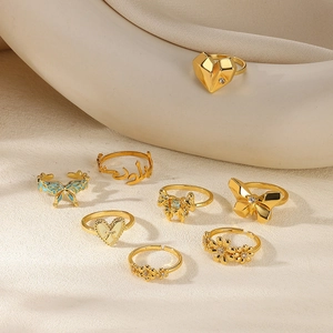 Set of 8 gold minimalist rings with butterfly, heart, and floral designs on white props