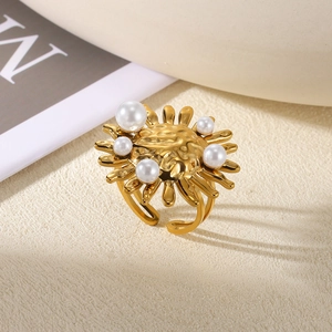 Macro shot of gold sunburst ring with scattered white pearls and hammered metal texture