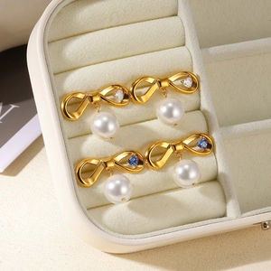 Vue macro de boucles d'oreilles nœud plaqué or 18K avec zircons et perles