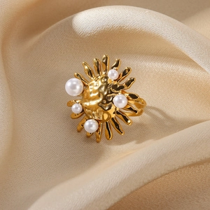 Detail of gold sun-shaped ring with white pearls and vintage hammered metal texture