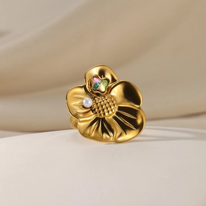 Macro detail of golden flower ring with pearl and heart-shaped zircon on beige fabric